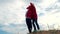 4k. Little boy and girl having fun playing wrapping national Canada flag outdoors over blue sky at summer - Canada day