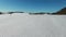 4K. Low flight and takeoff above snow fields in winter, aerial panoramic view. Winter land in the north