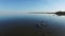 4K. Magic flight with birds over the sea at sunset above stones in the water, aerial view