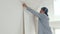 4K. Man applying a roll of wallpaper to the wall, smoothes pasted wallpaper