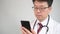 4K. Middle-aged Asian male doctor who uses a smartphone to take telemedicine.
