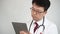 4K. Middle-aged Asian male doctor who uses a tablet computer to take telemedicine.