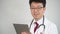 4K. Middle-aged Asian male doctor who uses a tablet computer to take telemedicine.