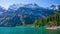 4K morning timelapse with sunbeams of Oeschinen Lake in the Swiss Alps near Kandersteg, Switzerland. Fishing boats on the emerald