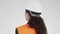 4K portrait of young serious dark-haired woman in white hard hat and orange reflective safety vest. 360 degree tracking