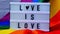 4k Rainbow flag with lightbox and text LOVE IS LOVE. Rainbow lgbtq flag made from silk material. Symbol of LGBTQ pride