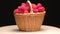 4K. Ripe raspberries in a wicker basket rotate on a black background