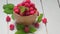 4K. Ripe raspberries in a wooden plate rotation a white wooden table.