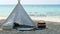 4K. romantic white picnic tent with basket food on white sand beach with crystal clear water and blue sky at background