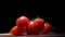 4k. A row of cherries tomato with water drops swings on a black and white background Macro. A narrow zone of sharpness. Close up.