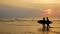 4K. silhouette of young happy surf man and woman running with long surf boards at sunset on tropical beach. surfer on the beach