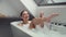 4K slow-motion footage of happy woman in foamy bath shaving legs