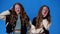 4k slow motion video of twin girls yawning over blue background.