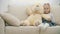 4k slowmotion video of little girl on sofa hugging her teddy bear.