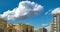 4k Time lapse clip of white fluffy rolling clouds against the background of yellow multi-storey apartment buildings