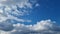 4k time lapse. Large swirling white clouds move across the blue sky.