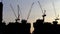 4K Time lapse of silhouette view tower cranes at construction site