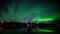 A 4k timelapse of Aurora Borealis dancing over a half-frozen lake with reflection from the water