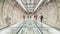 4K UHD time-lapse of unidentified people walking in subway tunnel walkway, zoom out then still