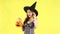 4K video of asian girl in halloween theme costume witch hat carrying orange pumpkin bucket posing on yellow background