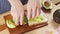 4k video, chef prepare sandwich by used hands pick avocado flesh piece into bread. Cooking healthy food on wooden tray.