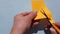 4k video. Close-up of female hands cutting orange paper with small scissors