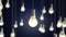 4k video of hanging light bulbs with glowing isolated on dark blue background.