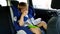 4k video of little toddler boy eating while riding in car. Child sitting in safety car seat and eating cookie
