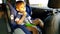 4k video of little toddler boy eating while riding in car. Child sitting in safety car seat and eating cookie