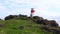 4K video of middle aged man walking path up to Lighthouse in Aberdour