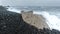 4k video of ocean waves braking on cliff on vulcanic black sand beach on cloudy day