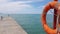 4k video, Orange lifebuoy on a pole on a background of blue sky and azure sea. Two little girls sisters in panama hats