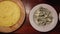 4k video of a plate of very hot traditional creamy polenta, a plate of gorgonzola cheese and a plate of walnuts