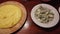 4k video of a plate of very hot traditional creamy polenta, a plate of gorgonzola cheese and a plate of walnuts