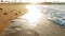 4k video of sea waves rolling over footprints on wet sand on the beach at sunset light