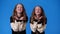 4k video of twin girls sending an air kiss over blue background.