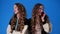 4k video of twin girls talking over the phone over blue background.