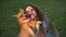 4k video Welsh Corgi Pembroke dog kiss his girl owner on the grass. Lifestyle with domestic playful pet. Young woman hug