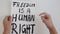 4k video of woman holding protest poster with words `Freedom is a Human Right`.