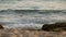 4K. Wave foam bubble of the sea on the beach with rock. tropical summer sea beach for holiday background footage, selective focus.