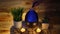 4k, Woman adding essential oil to electric diffuser lamp, candles on wooden table in room