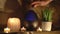 4k, Woman adding essential oil to electric diffuser lamp, candles on wooden table in room