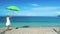 4k Young girl in a white dress with a green umbrella in her hands is raised by the wind over a pebble beach against the backdrop o