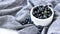 4k zoom in out Small White Bowl of Organic Blueberries on Wooden Table with kitchen towel. Summer fruit berries