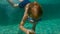 4x times slowmotion shot of a cute little boy jumping into pool and knocking to pebbles under water