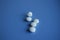 5 vitamins or pills, one vertical, four laid flat, on blue background copy space