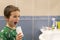 A 5-year-old boy at home washes his teeth with an oral irrigator. Little boy cleaning teeth with oral irrigator. Dental Care