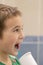 A 5-year-old boy at home washes his teeth with an oral irrigator. Little boy cleaning teeth with oral irrigator. Dental Care