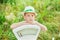 5 years old boy in summer hat sit on ground with his hands on white old fashioned scales. Summer time. Children play outside in