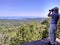 50 year old man views wild expanse of forest and water through binoculars